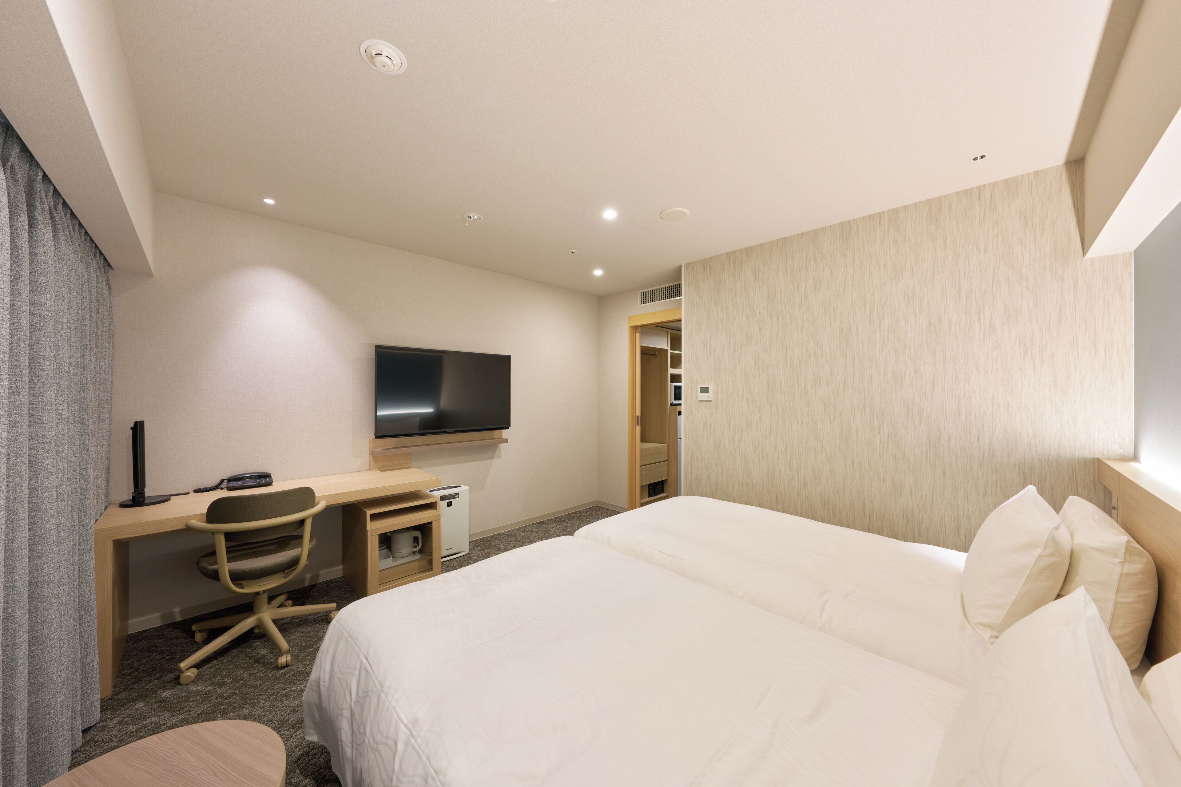 Una camera d'hotel con un letto grande, una scrivania con un computer, una televisione e un armadio.