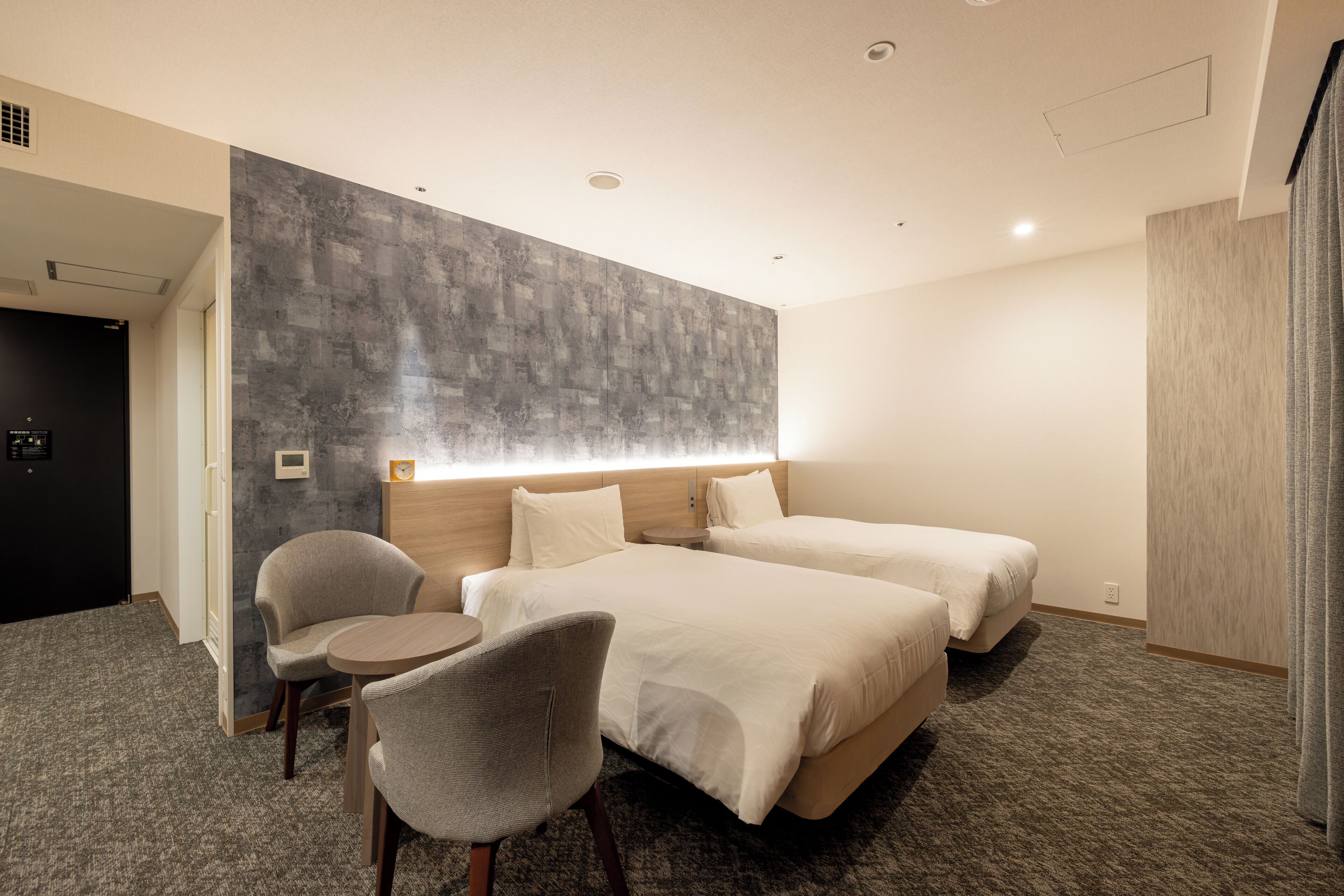 A hotel room with two beds, a desk, and a chair.