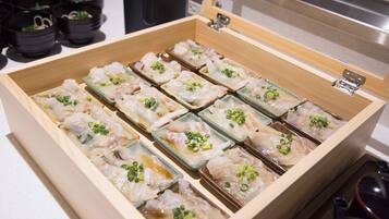 A wooden box containing neatly arranged sashimi pieces garnished with green onions.