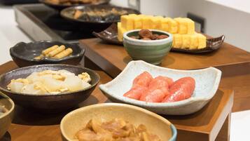 A variety of dishes on a wooden table, including what appears to be dumplings, sliced watermelon, and other food items.