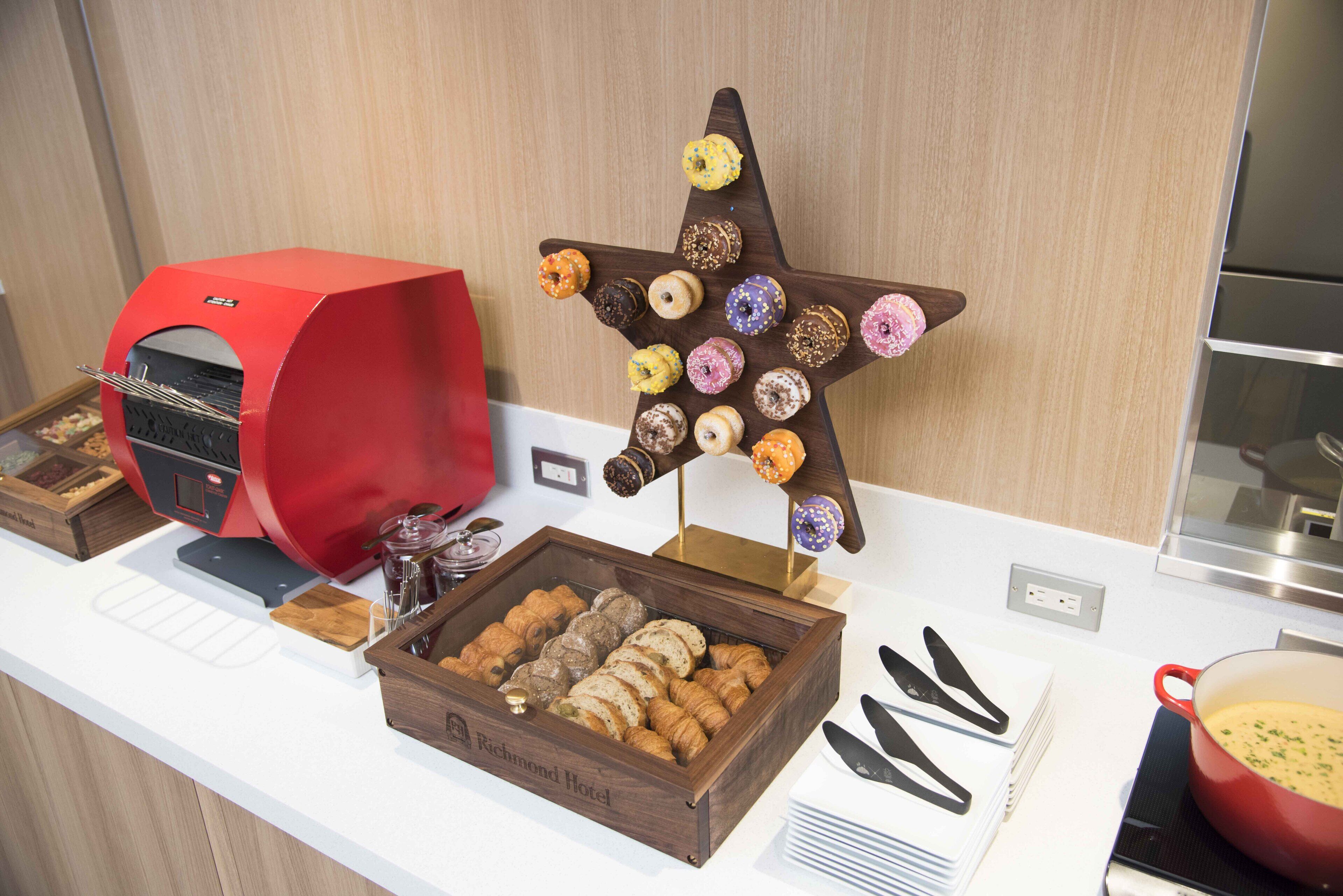 A breakfast buffet with a variety of pastries and a doughnut display.