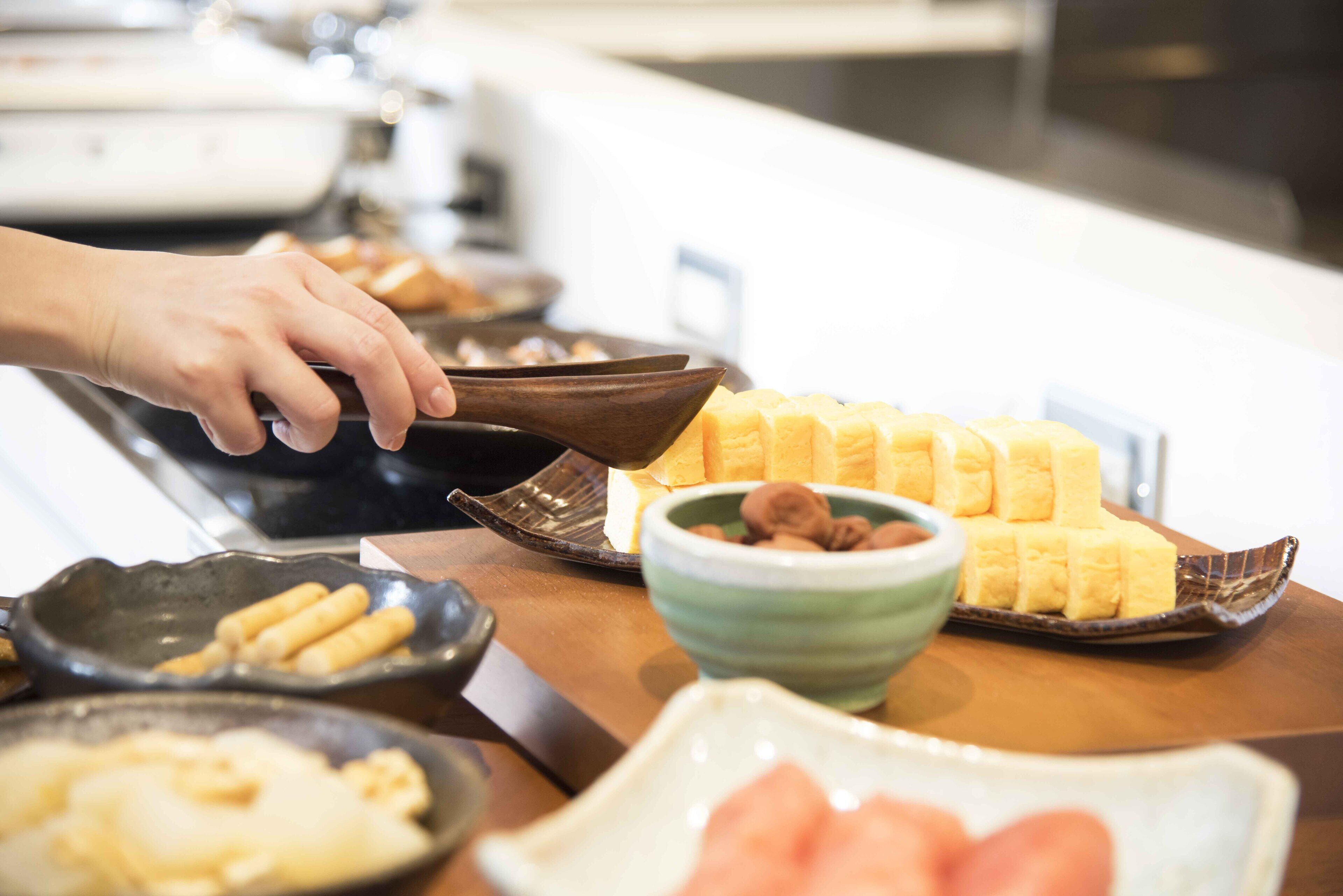 Buffet com diversos pratos, incluindo pão, bananas e um recipiente com nozes.