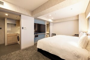 Habitación de hotel con una cama grande, lavadora, kitchenette y baño.