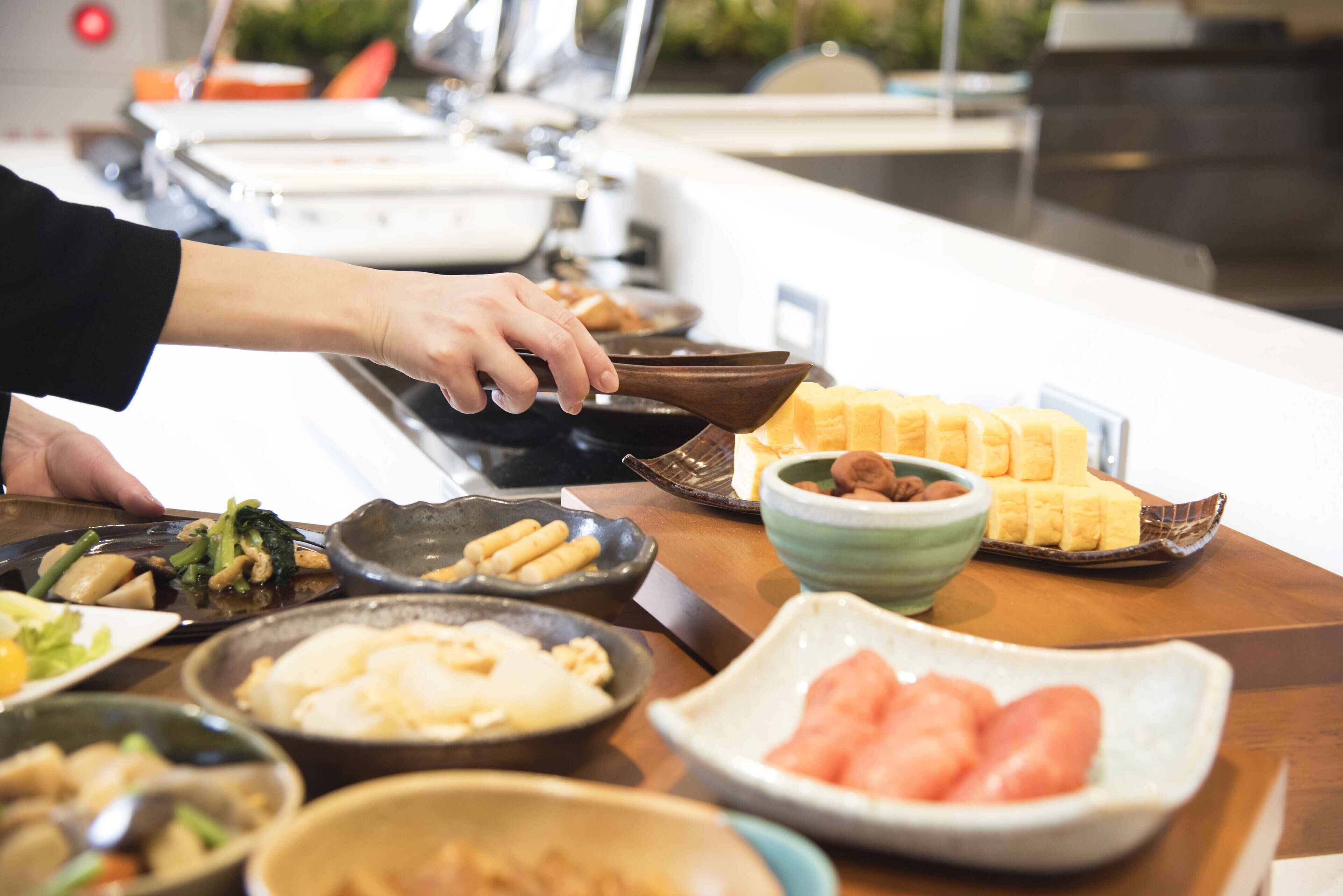 A buffet table with various dishes including a bowl of watermelon, a plate of bread, and several other dishes.