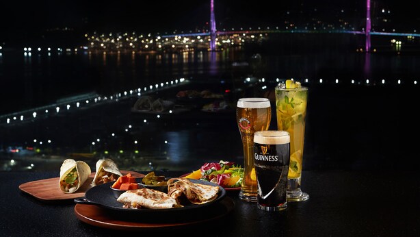 A table with food and drinks, a view of a bridge, and city lights in the background. - Asti Hotel Busan Station (Busan)