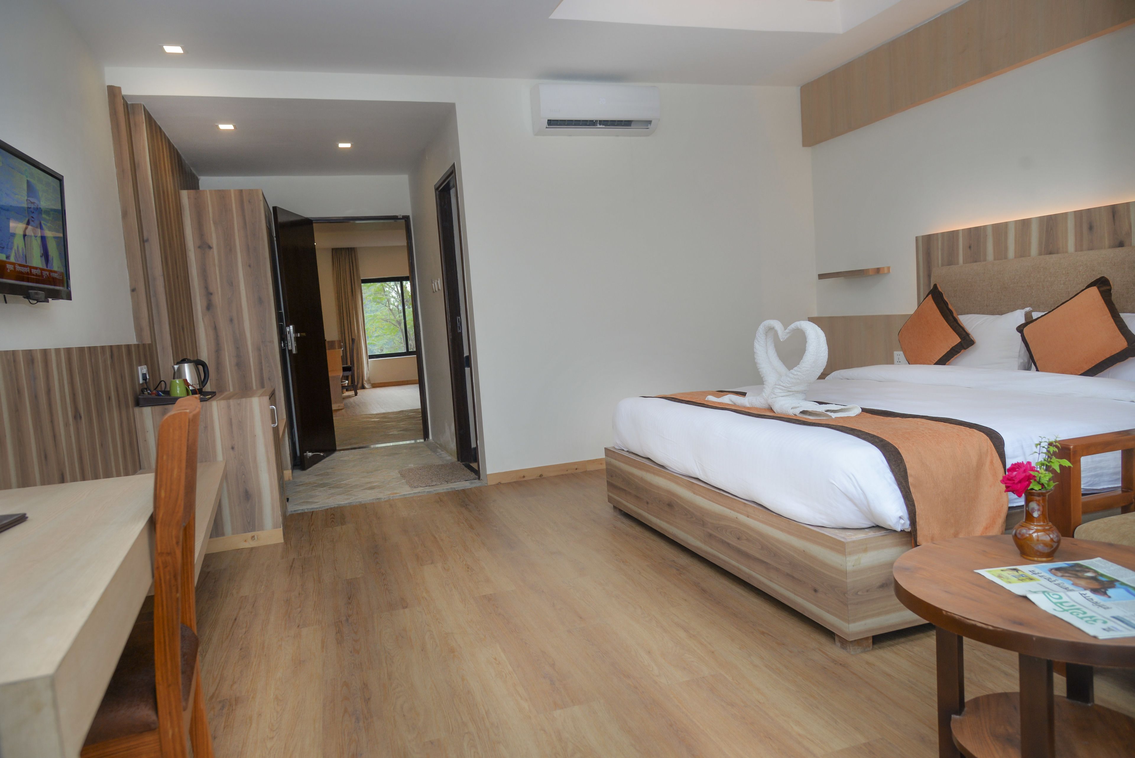 A modern hotel room with a wooden bed, a desk, and a chair.