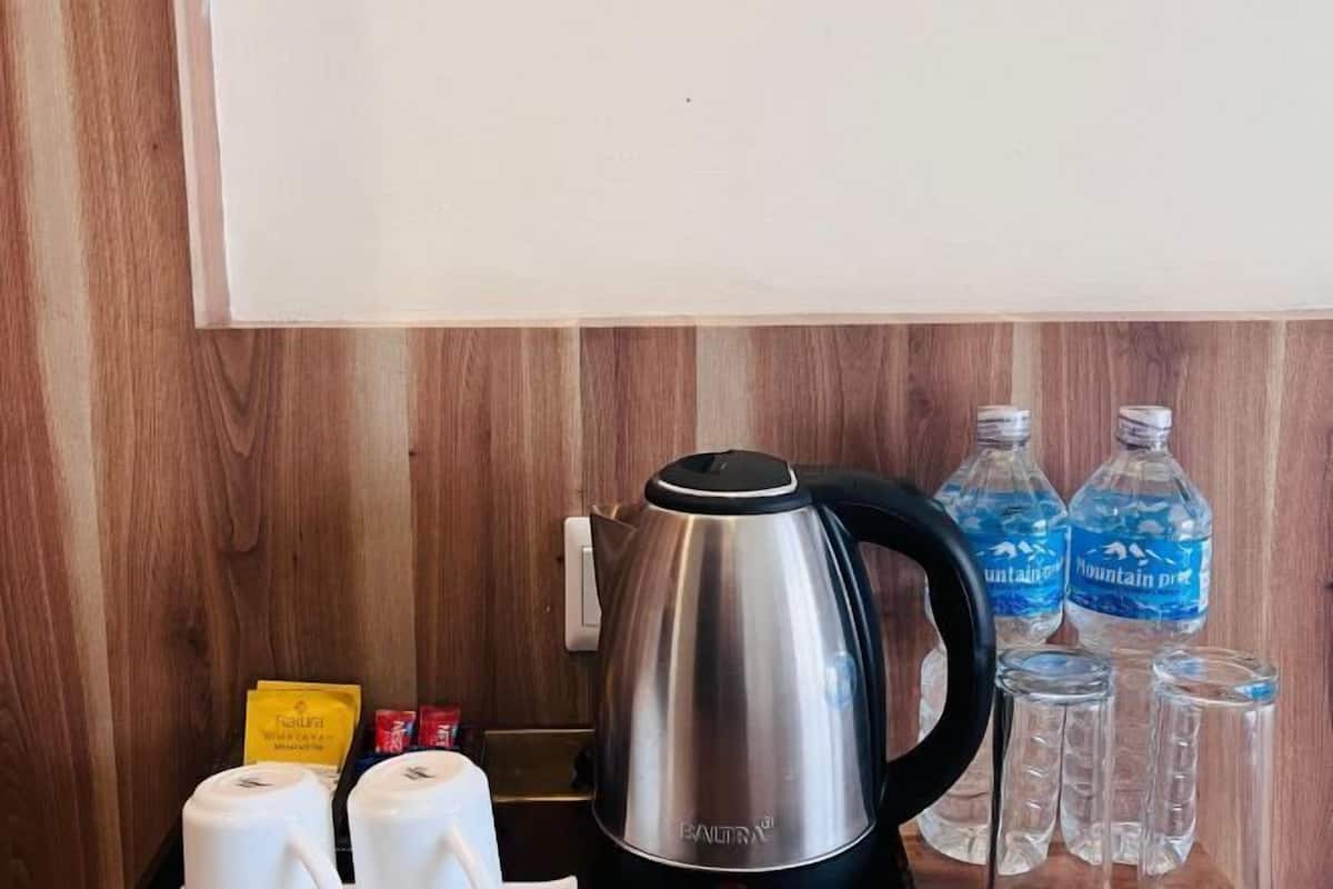 A stainless steel kettle, water bottles, and condiment packets on a wooden surface.