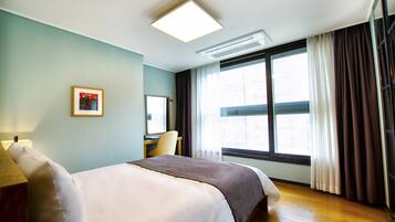 Habitación de hotel con cama, escritorio y ventana con cortinas.