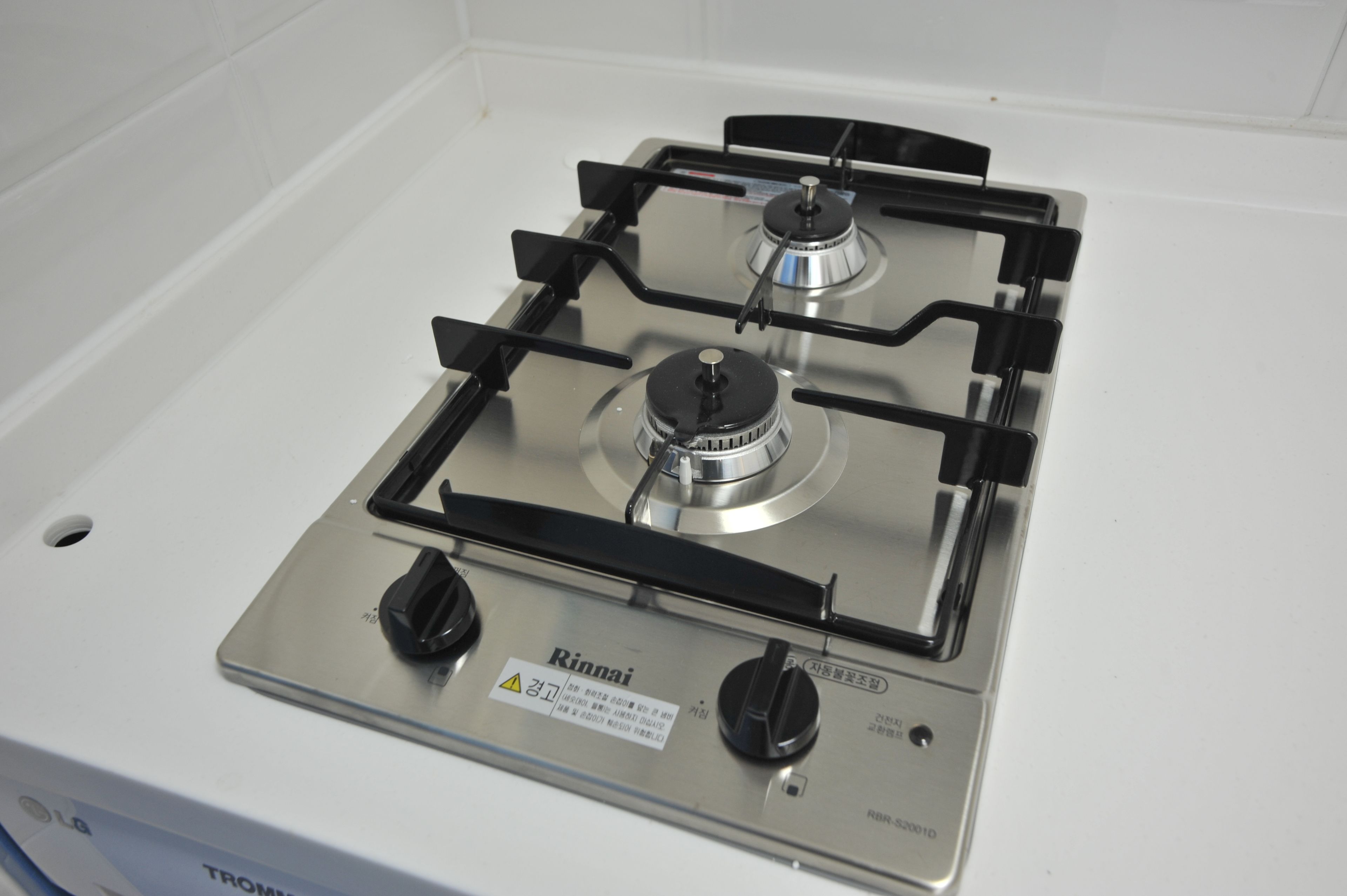 A stainless steel gas stove with four burners and two knobs, labeled "Rinnai."