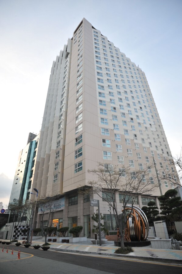 A tall, modern building with multiple floors, large windows, and a central entrance. - Plea De Blanc (Busan)