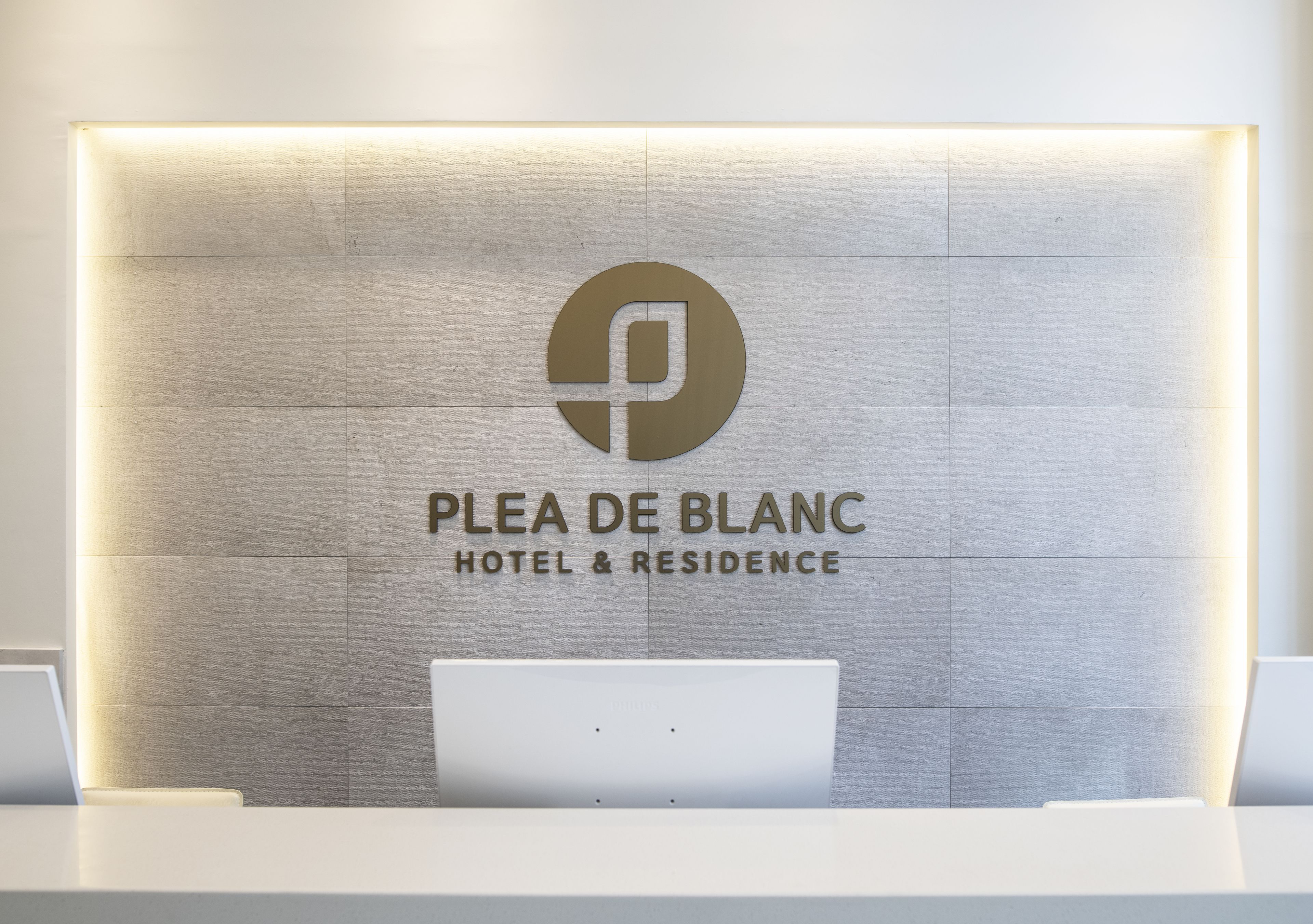 Uma receção com um letreiro a dizer "PLEA DE BLANC HOTEL & RESIDENCE".