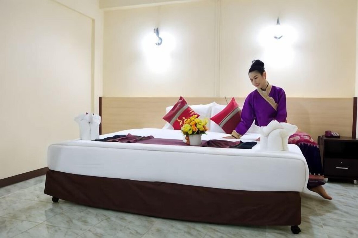 Habitación de hotel con cama, mesita de noche, lámpara de pared y aire acondicionado de pared.