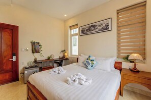 A hotel room with a bed, bedside table, desk, and a window with blinds. - Hoi An Green Town House Homestay (Da Nang)