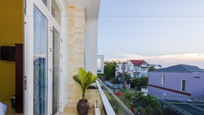 A balcony with a potted plant, a glass door, and a view of neighboring houses.