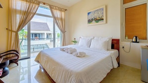 A hotel room with a large bed, a desk, a chair, and a window with curtains. - Hoi An Green Town House Homestay (Da Nang)