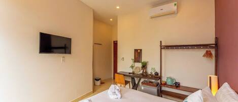 A hotel room with a bed, a desk, a television, and a ceiling fan.