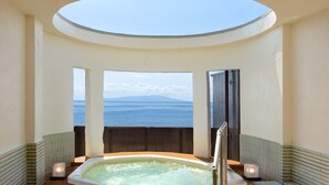 Een jacuzzi met uitzicht op zee en bergen, een dakraam en een houten terras.
