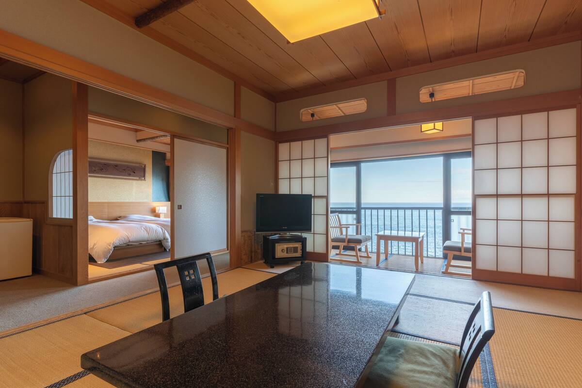 A traditional Japanese-style room with tatami flooring, a low table, and a futon bed.