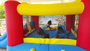A large inflatable bouncy castle with a netted enclosure, featuring a blue and yellow floor and red and yellow sides. - Mais oui Tennis and Spa Villa (Rio Bueno)