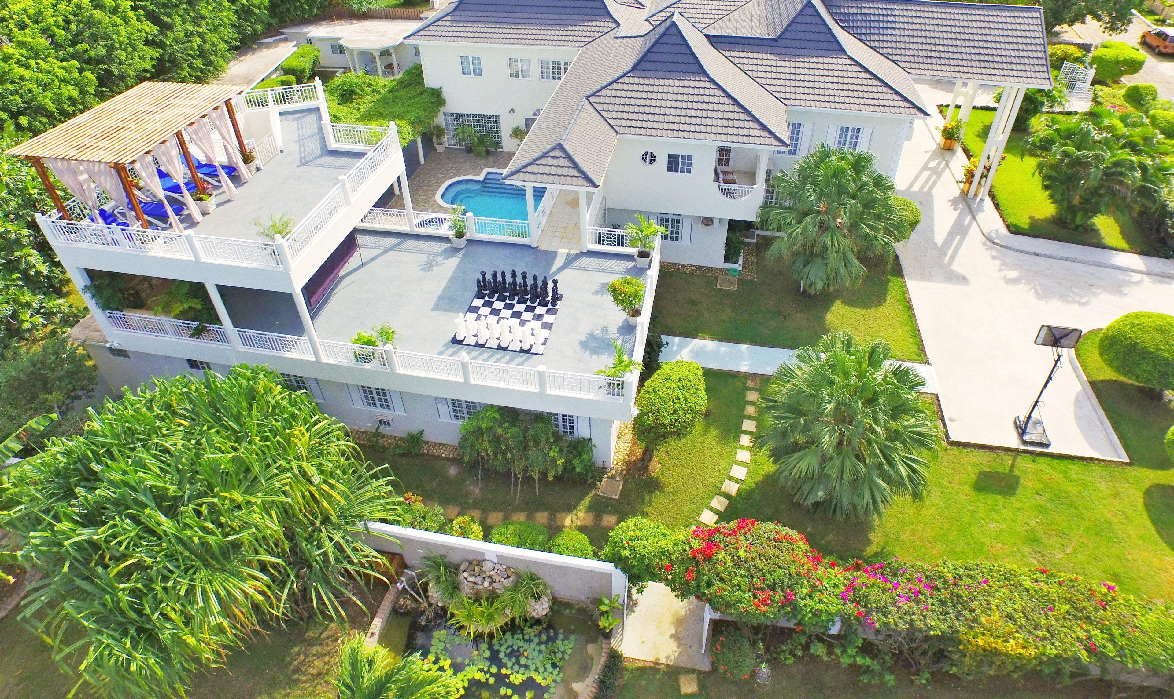 Ein großes, zweistöckiges Haus mit Swimmingpool, mehreren Balkonen und einem gepflegten Garten.