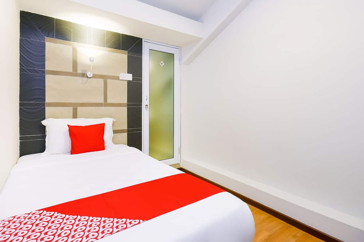 A hotel room with a bed, a wardrobe, and a door with frosted glass panels.