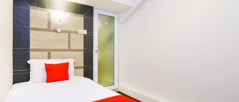 Una habitación de hotel con cama, armario y puerta con paneles de vidrio esmerilado.