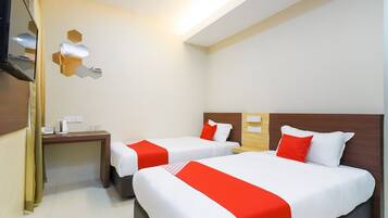A hotel room with two beds, a desk, a television, and a wall-mounted light fixture.