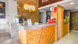 Un comptoir d’accueil avec une façade en bois, une enseigne indiquant « OYO » et un drapeau malaisien.