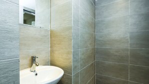 Une salle de bain avec un lavabo blanc, un miroir et des carreaux gris.