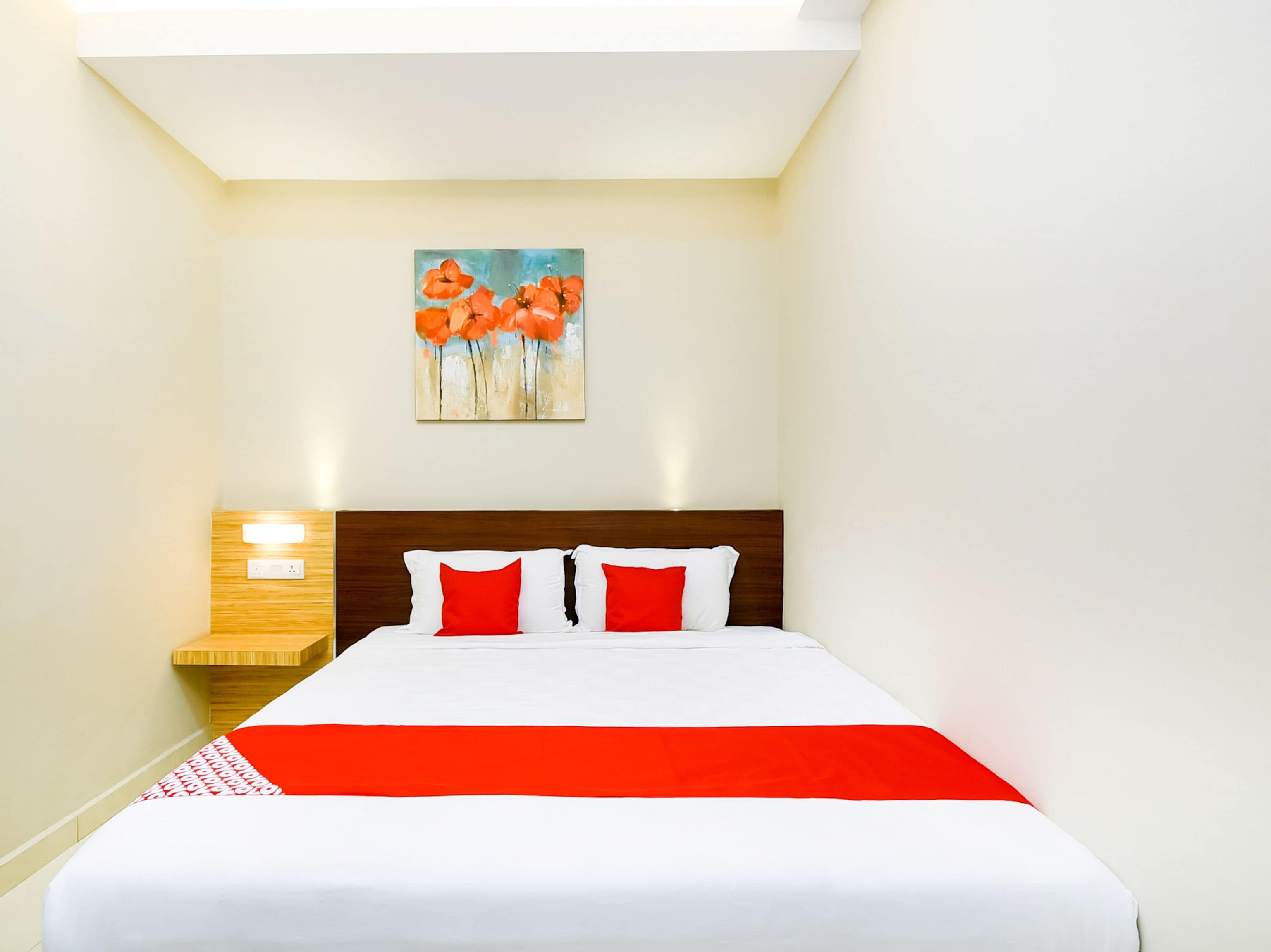 Une chambre d’hôtel avec un lit, une table de chevet, un tableau et un luminaire.