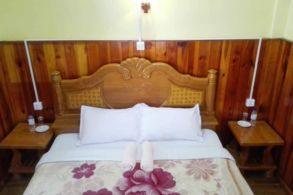 Una habitación con paneles de madera, una cama, dos mesitas de noche y una lámpara fijada a la pared.
