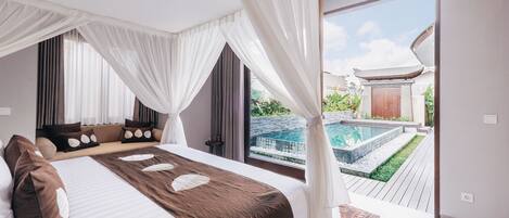 A bedroom with a large bed, white curtains, and a view of a swimming pool.