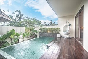 A private pool area with a wooden deck, a hanging chair, and lush greenery. - Daun Lebar Villas (Payangan)