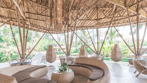 A bamboo-framed outdoor lounge area with wicker furniture and hanging light fixtures. - Daun Lebar Villas (Payangan)