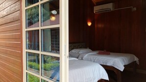 Een kamer met twee bedden, houten wanden en grote ramen.
