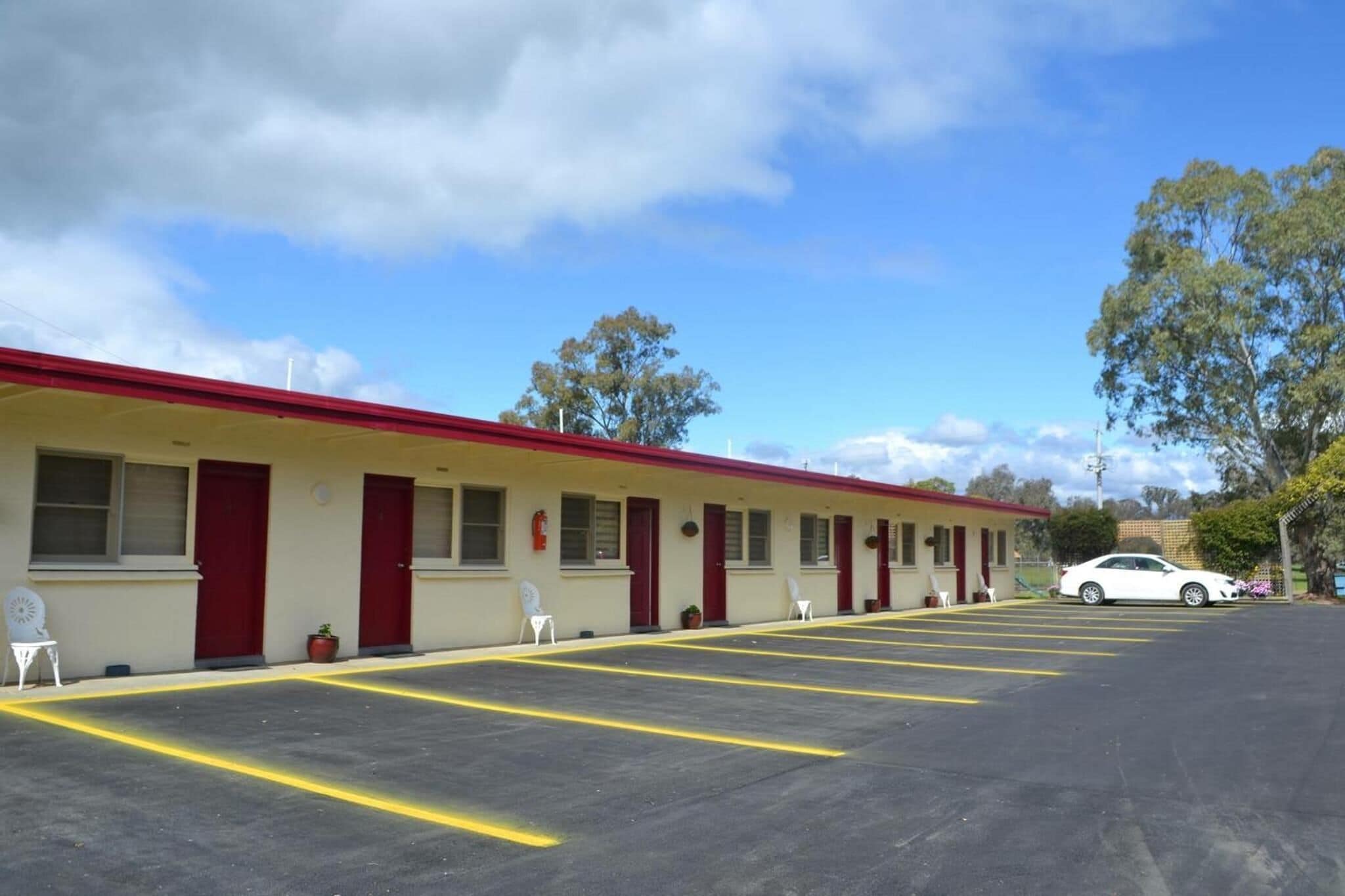A motel with a row of rooms, a parking lot, and a white car parked in front.