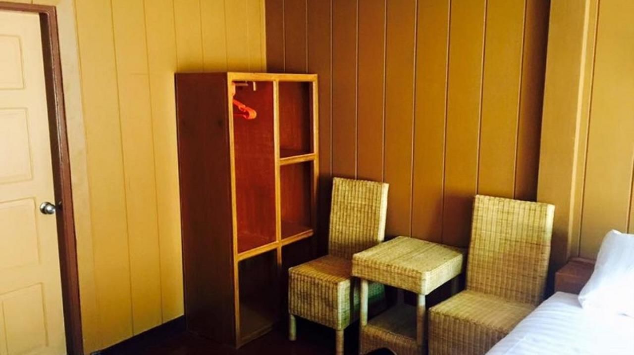 Una habitación con una cama, una mesita, dos sillas y un armario.