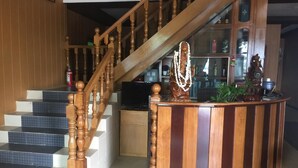 A staircase with wooden balusters, a curved reception desk, and a television in the background. - Golden Fish Motel (Nyaungshwe)