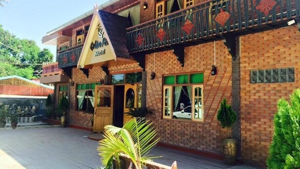 A hotel with a brick facade, a balcony with decorative railings, and a sign indicating it is a hotel. - Golden Fish Motel (Nyaungshwe)