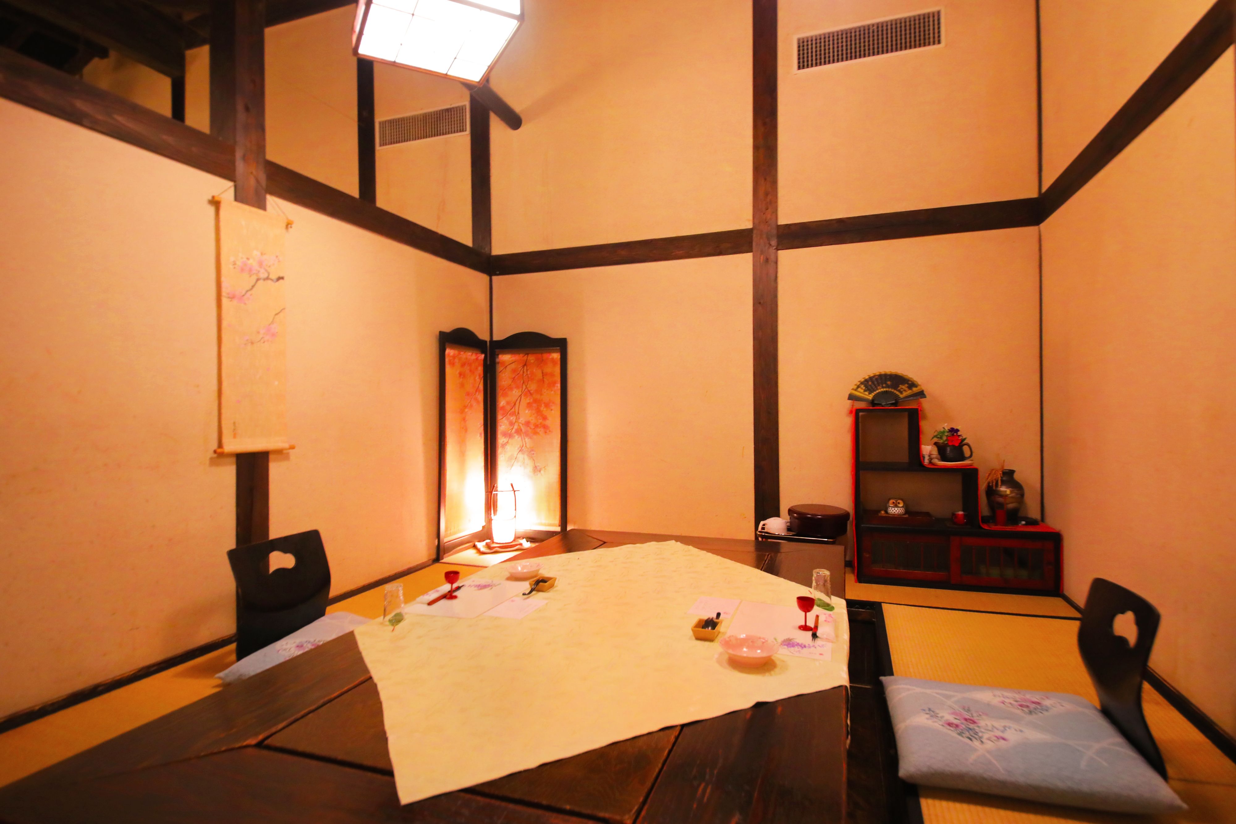 A traditional Japanese room with tatami flooring, a low table with a placemat, and a sliding door with a decorative screen.