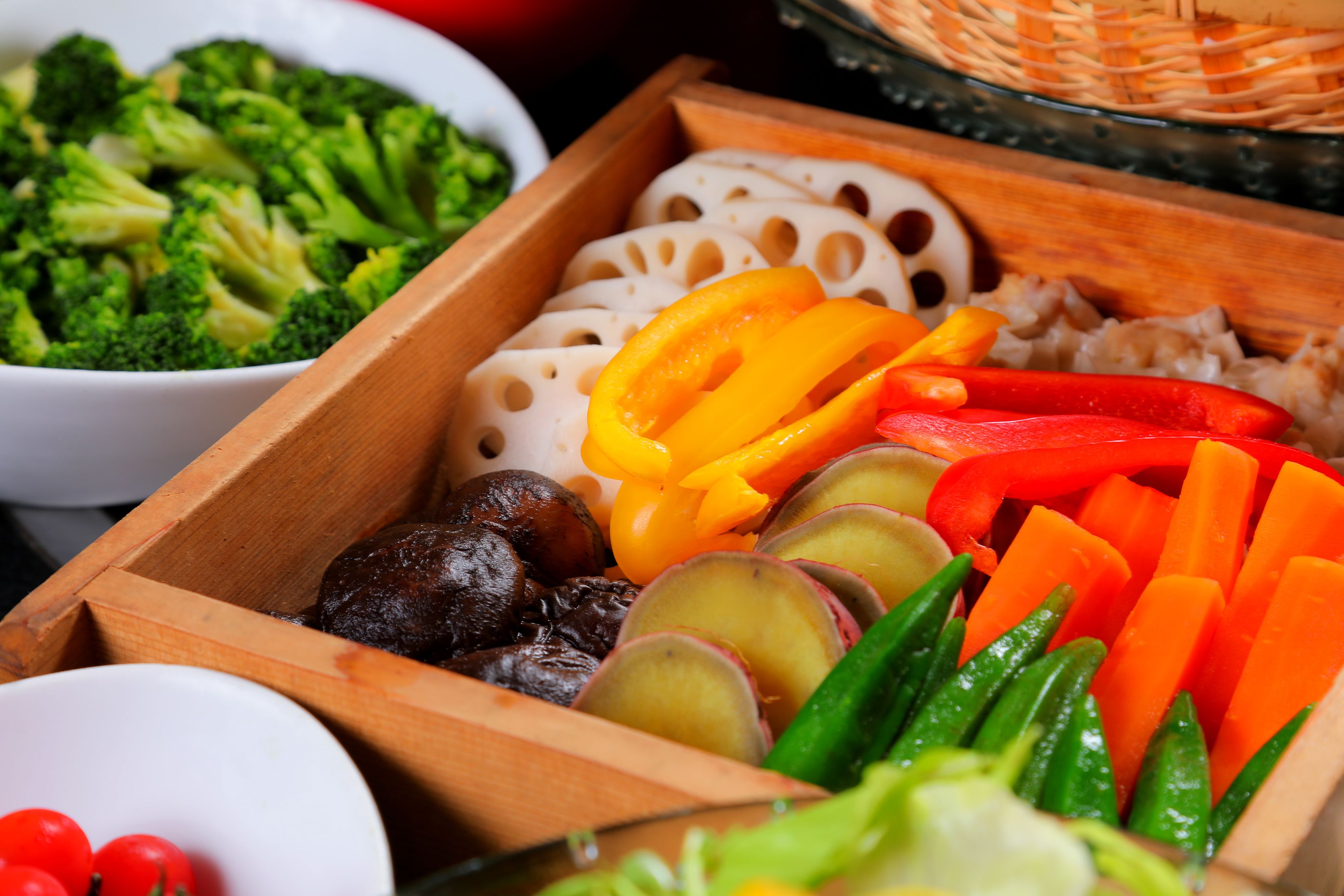 A wooden box containing various vegetables including broccoli, bell peppers, and carrots.