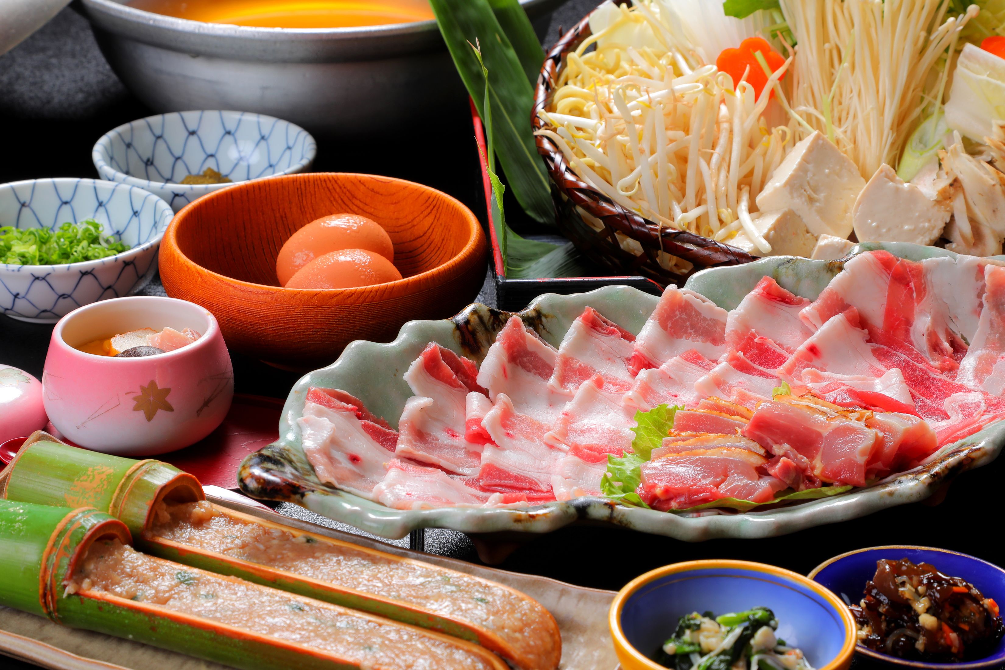 A variety of food items including sliced meat, vegetables, and bowls of condiments.