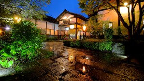 Un edificio japonés tradicional con un corredor cubierto y un pequeño estanque que refleja luces.