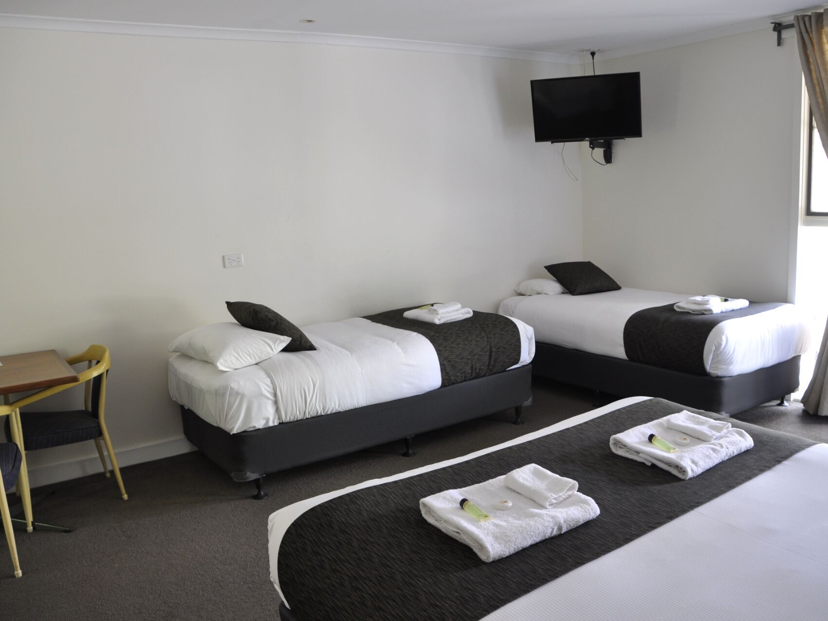 Habitación de hotel con dos camas, un escritorio y una televisión.
