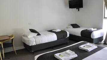 Habitación de hotel con dos camas, un escritorio y una televisión.