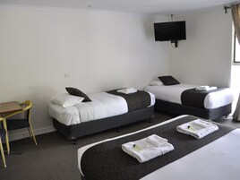 A hotel room with two beds, a desk, and a TV.