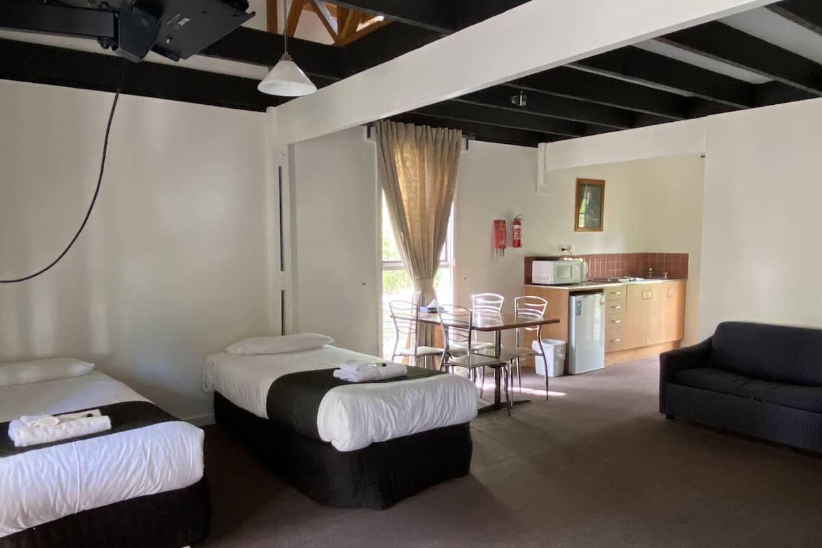 Habitació d'hotel amb dos llits, una taula de menjador amb cadires, una cuineta i un sofà.