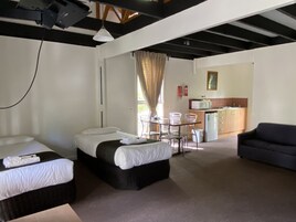 Habitación de hotel con dos camas, una mesa de comedor con sillas, una kitchenette y un sofá.