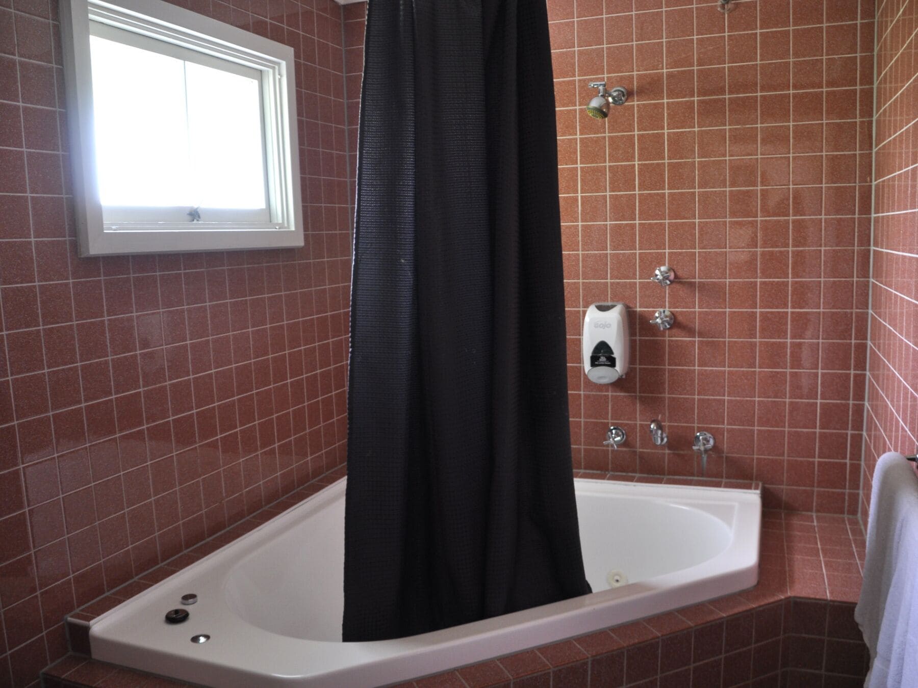 A bathroom with a bathtub, a window, and a shower control panel.