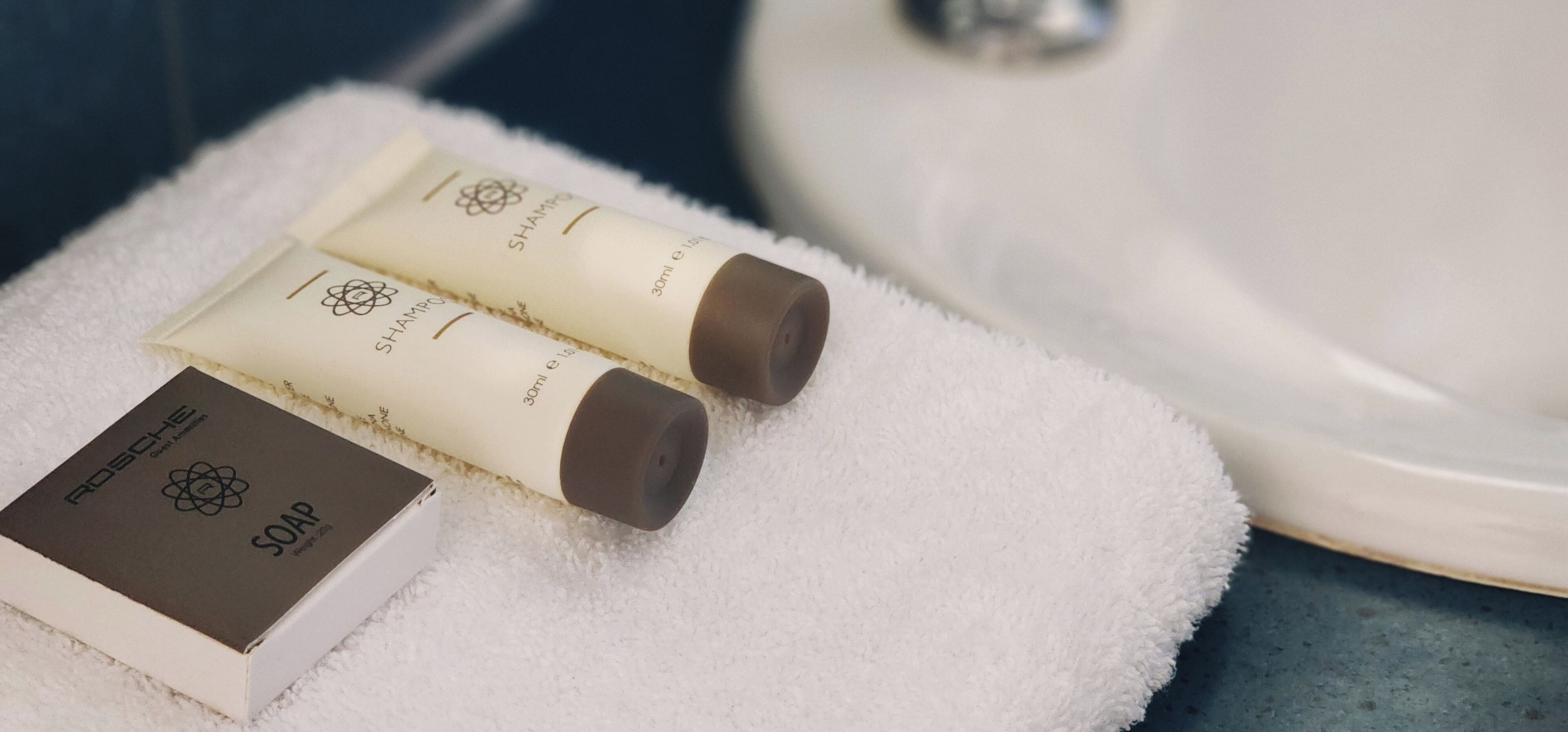 Two bottles of skincare products and a box of soap on a white towel.
